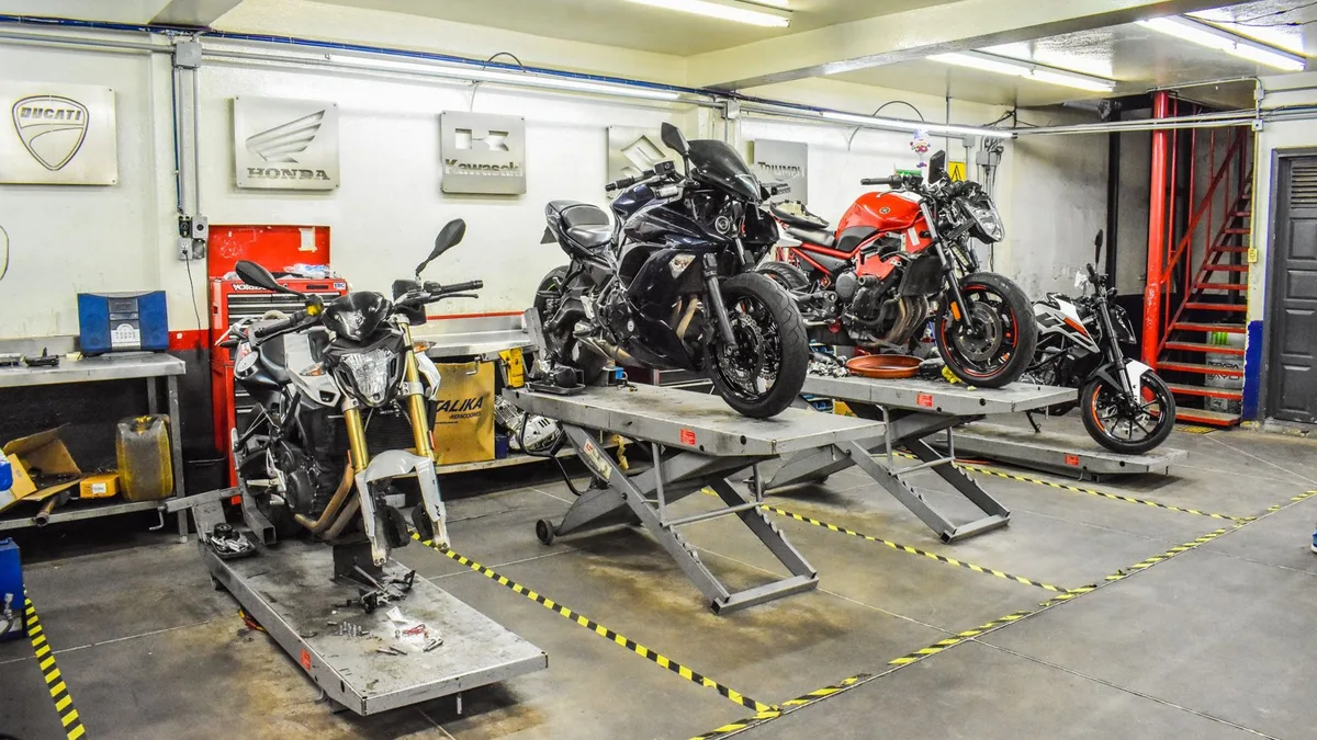 Lève-moto d'atelier sous une moto sportive, vue rapprochée du support et de la roue arrière relevée.